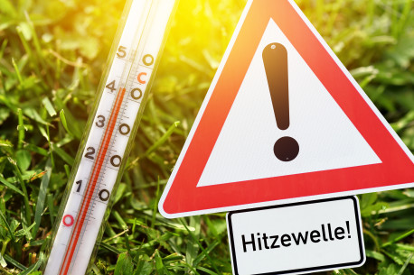 Thermometer und Warnschild Hitzewelle.